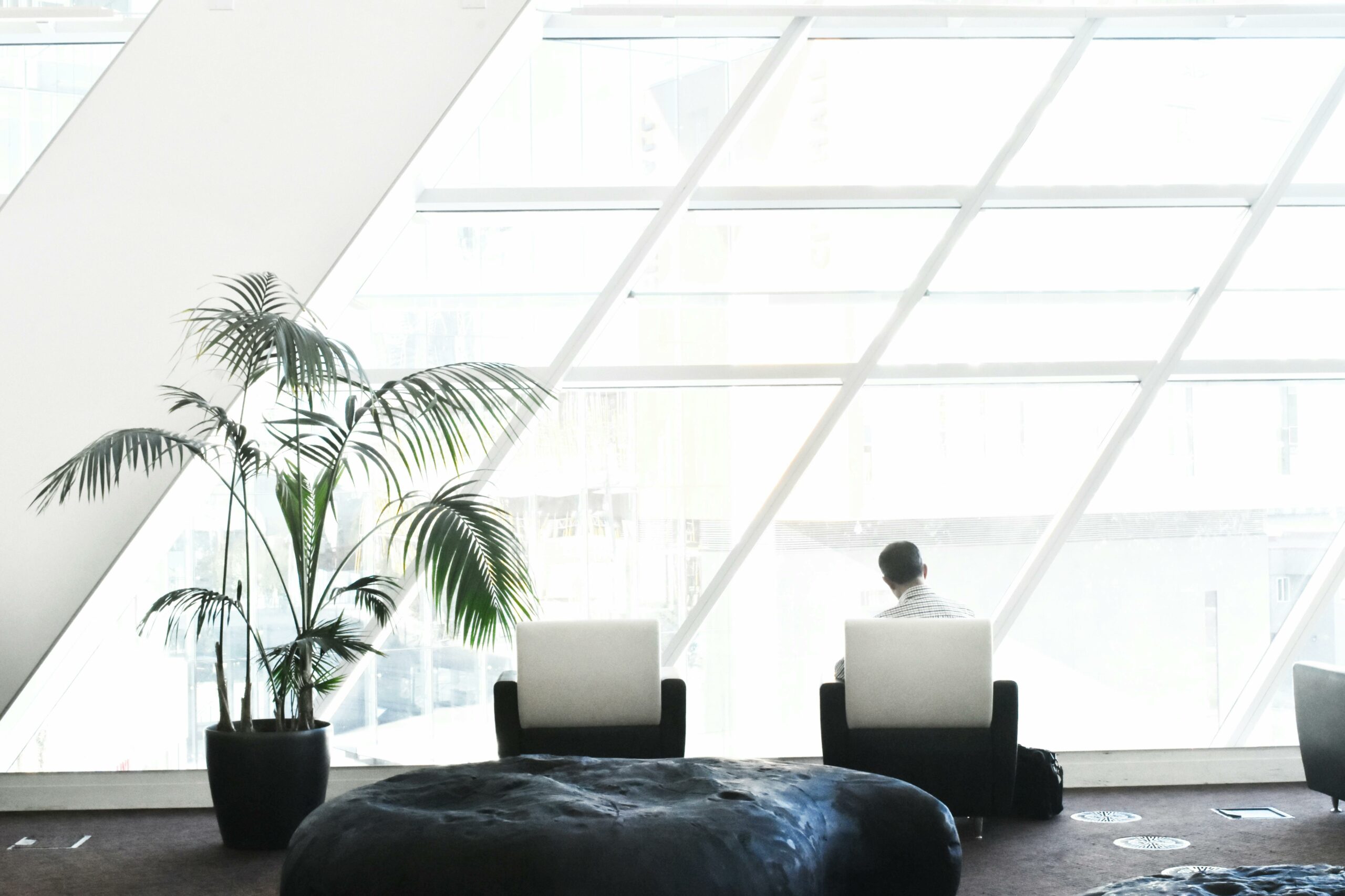 man sitting alone looking out window in modern office building